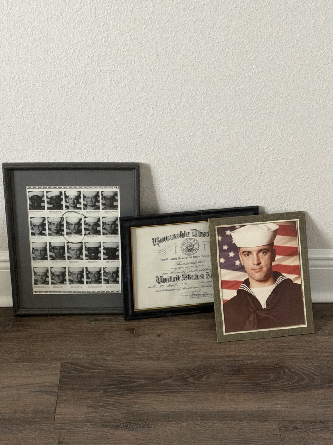 A framed portrait of a young sailor, his service certificate, and a contact sheet of photographs arranged on a wall in a new Florida home
